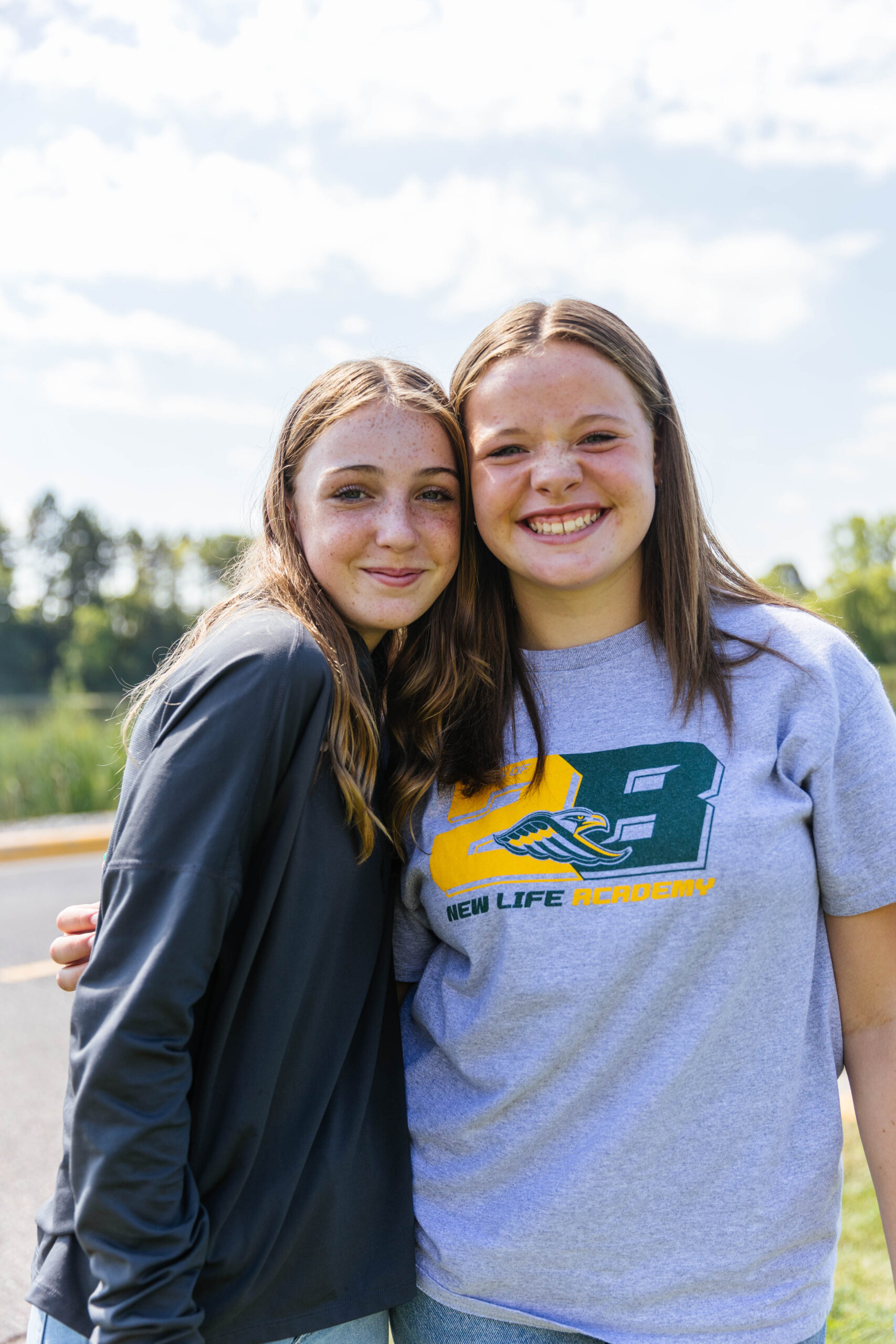 2 middle school girls standing outside smiling at the camera