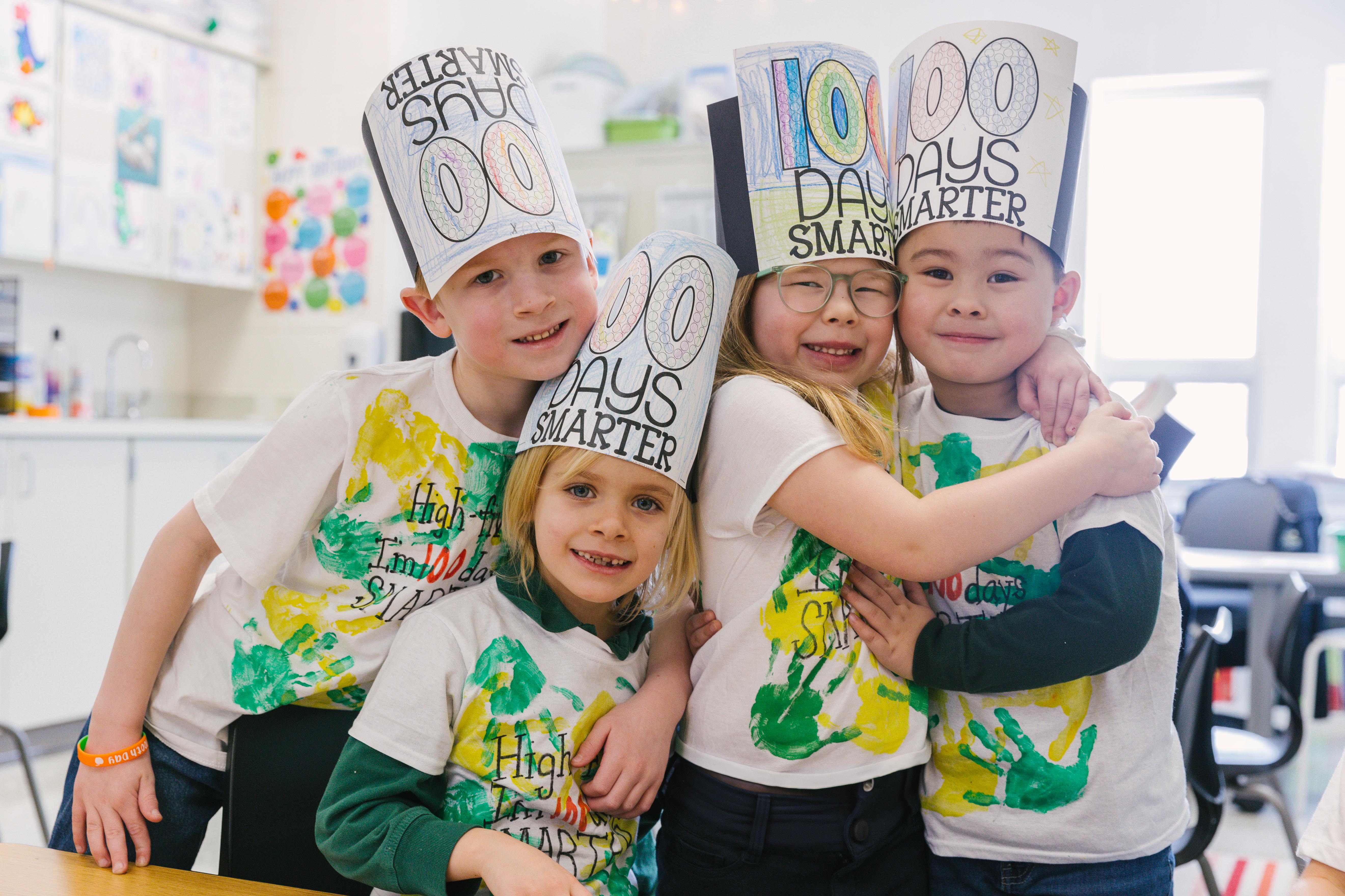 Kindergarten students sit around their classroom table learning from their teacher.