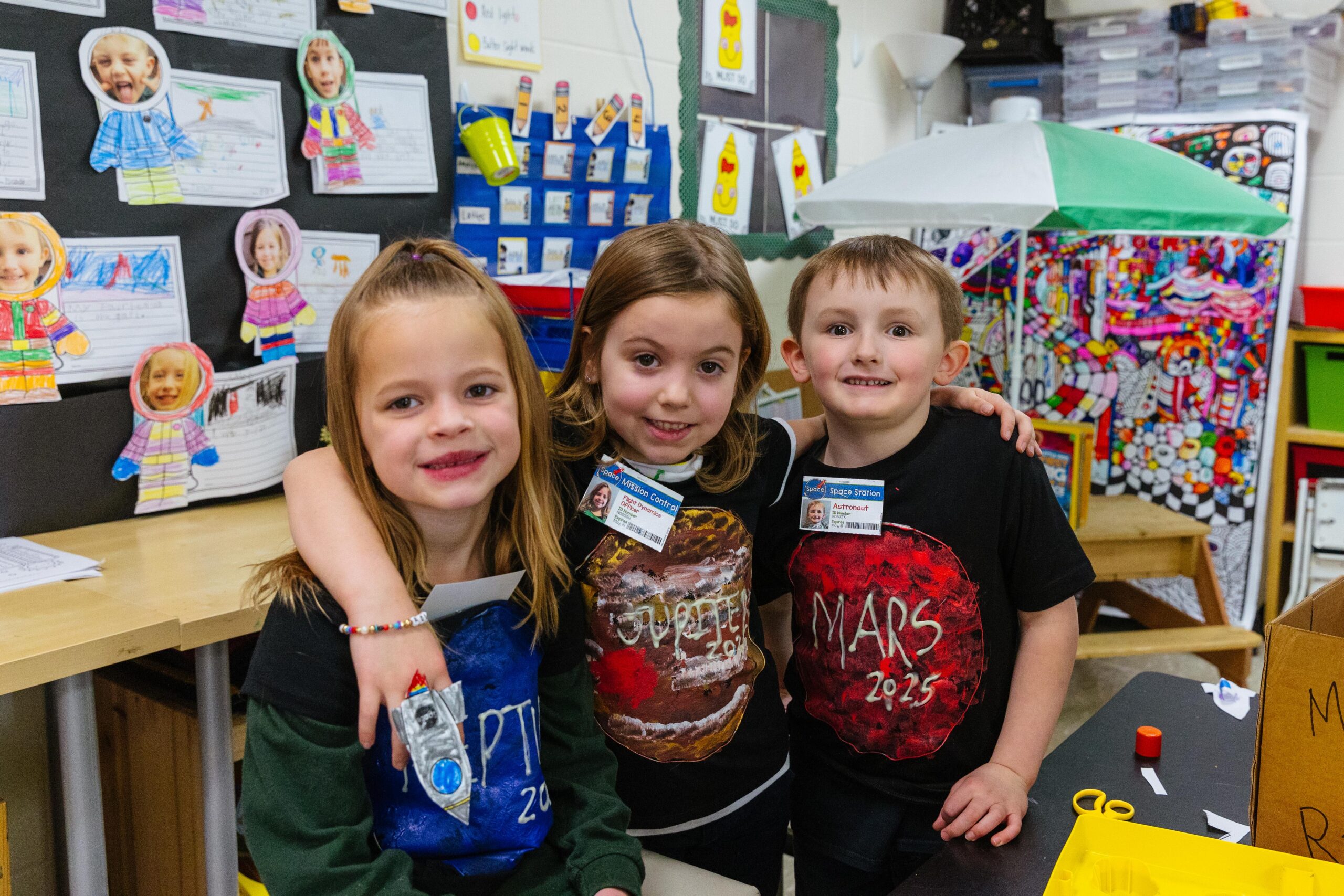 Kindergarten students sit around their classroom table learning from their teacher.