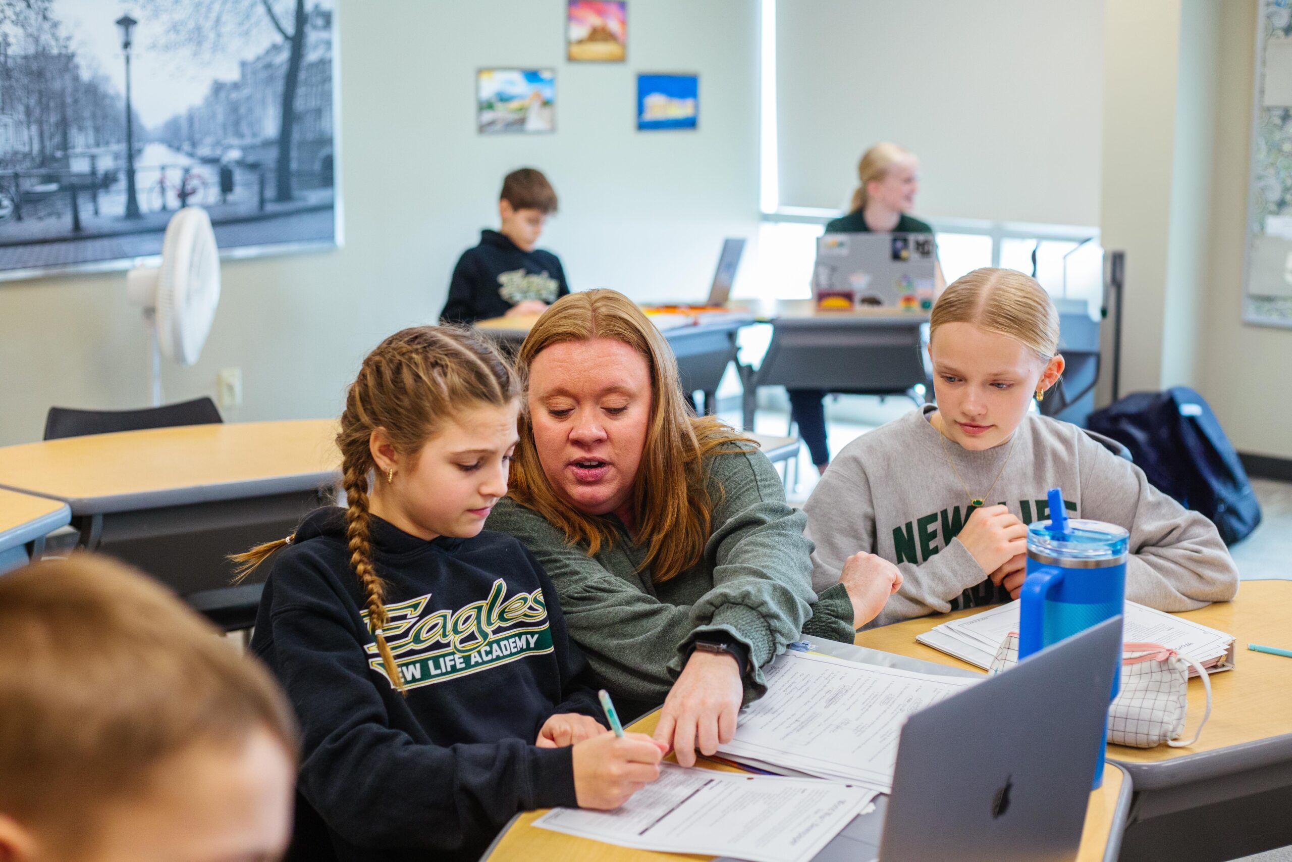 Science teacher at New Life Academy looks through a microscope as a middle school student watches and learns.