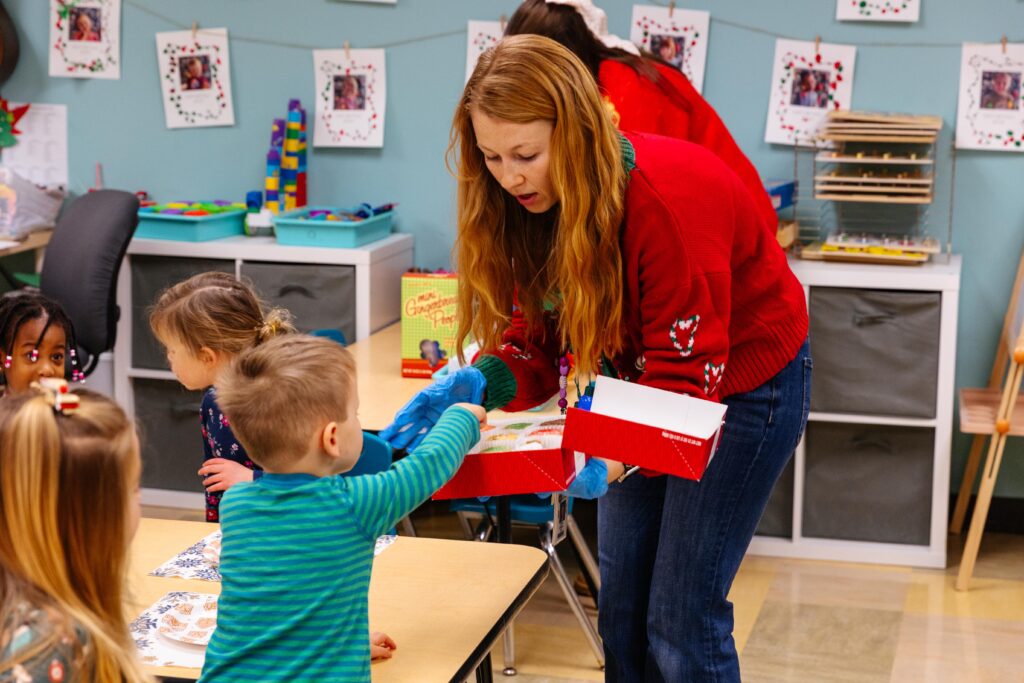 Christian school teacher assisting young students with a classroom activity during the Christmas season.