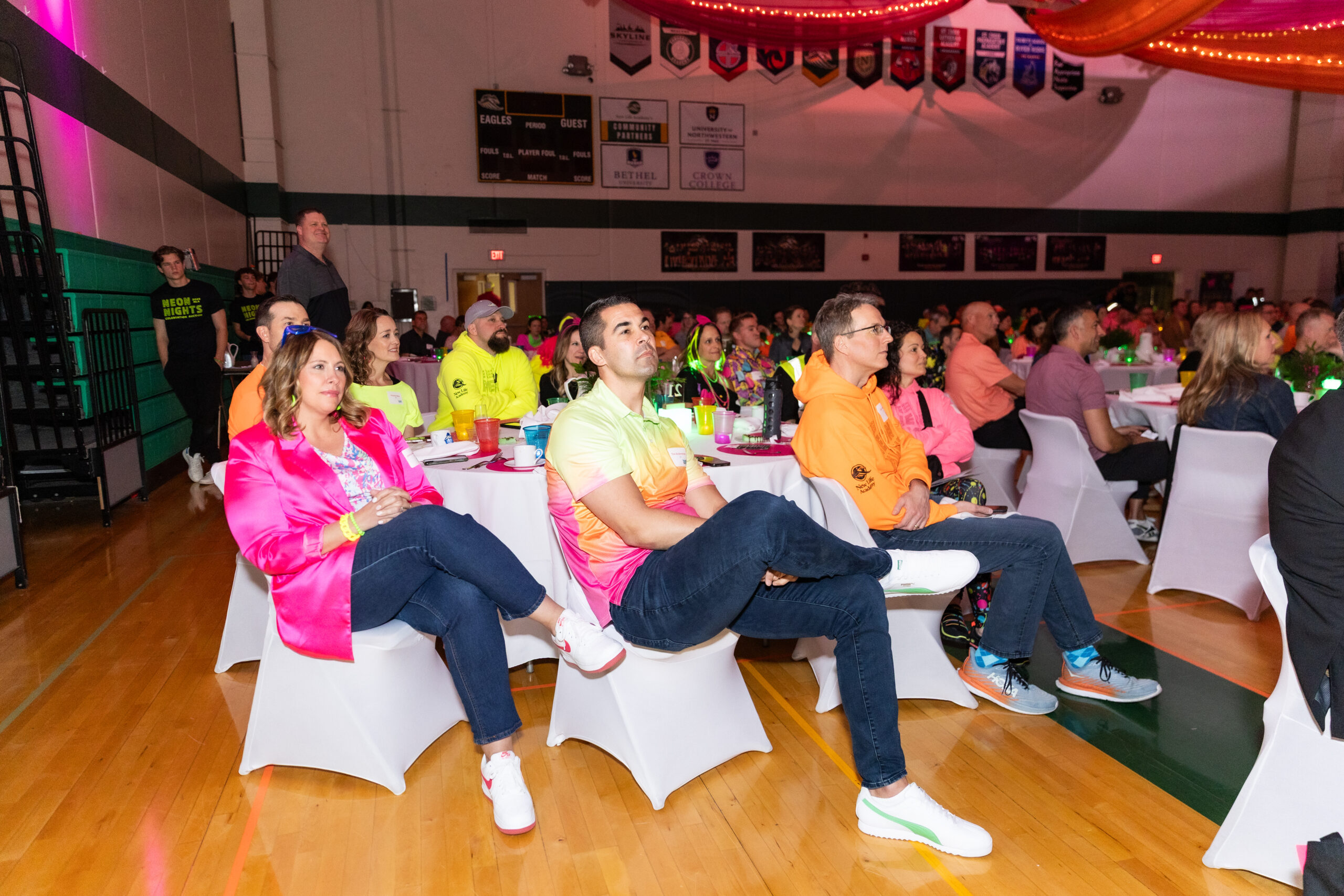 Guests seated in a decorated gym watching the program at New Life Academy’s Neon Nights Celebration Auction.