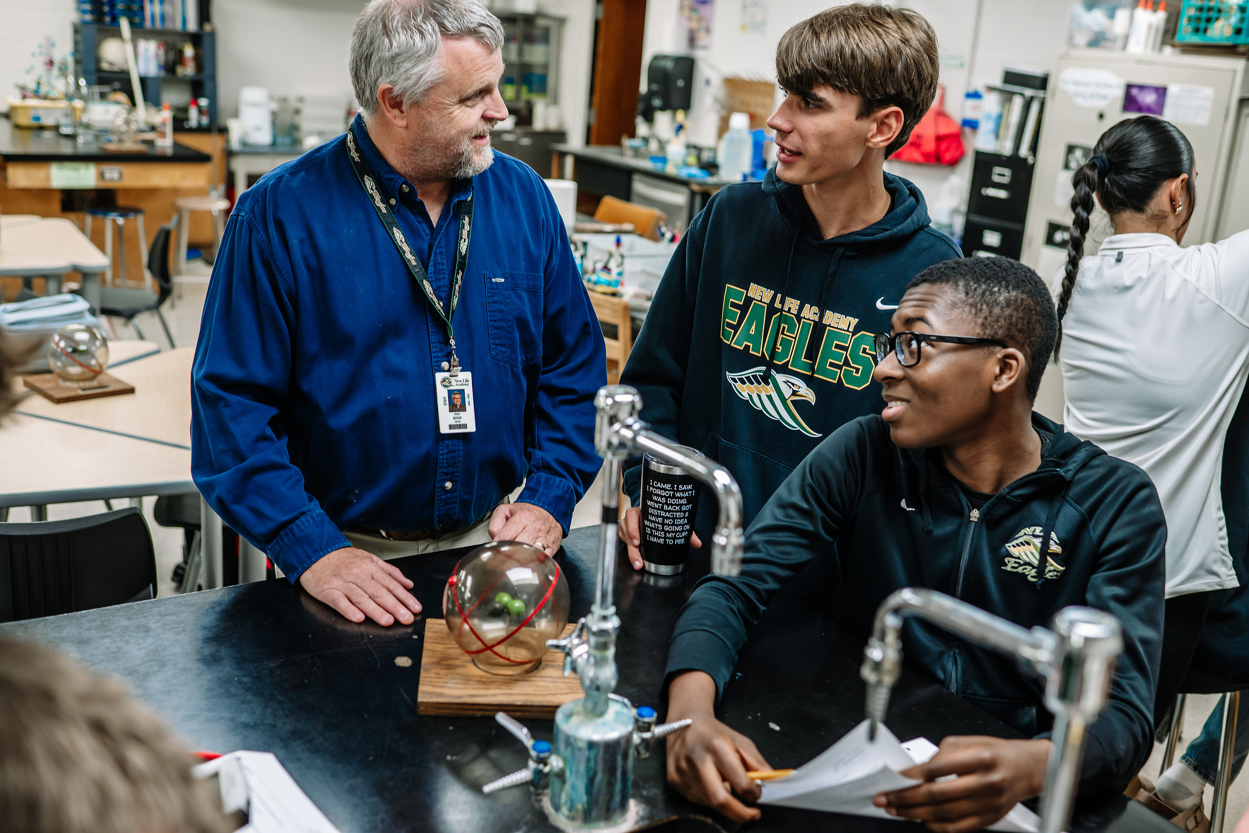 Science teacher engaging with students during a hands-on lab experiment at New Life Academy