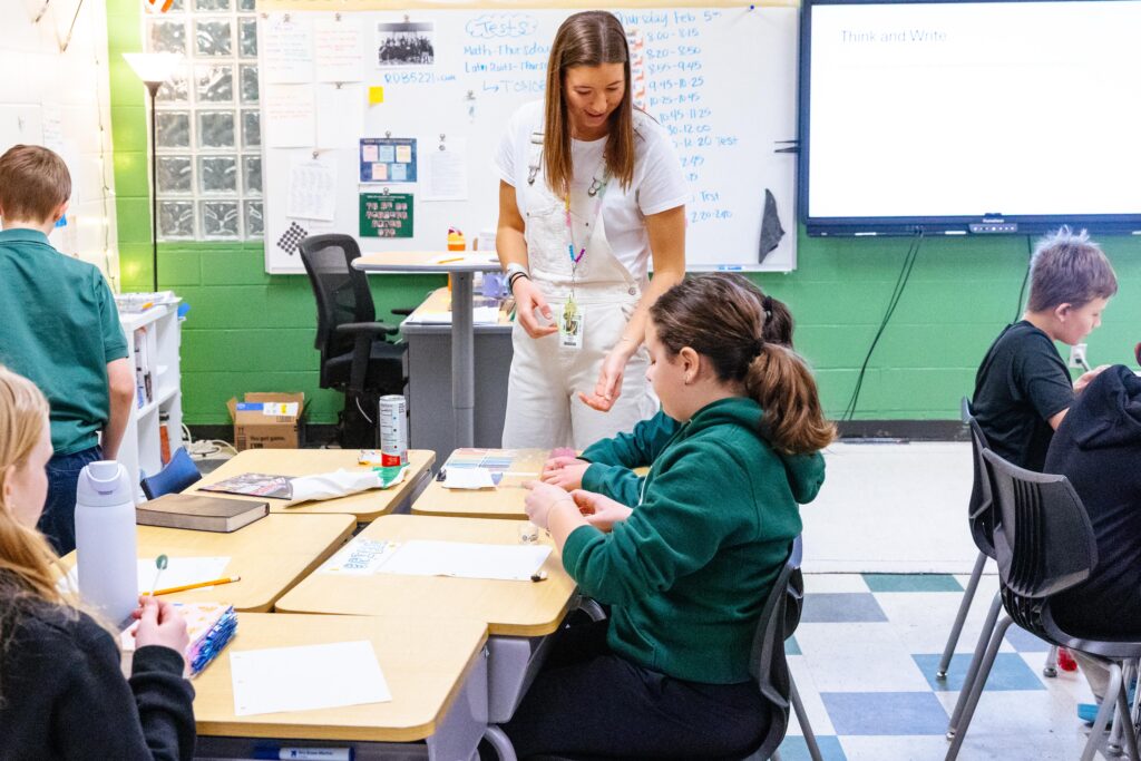 Fifth grade teacher working with students at their desks during a classroom activity at New Life Academy.