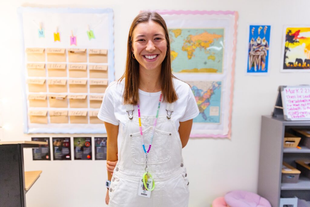 New Life Academy fifth grade classroom with a teacher standing in front of educational wall displays, used to introduce new fifth grade teacher Megan Bohlig