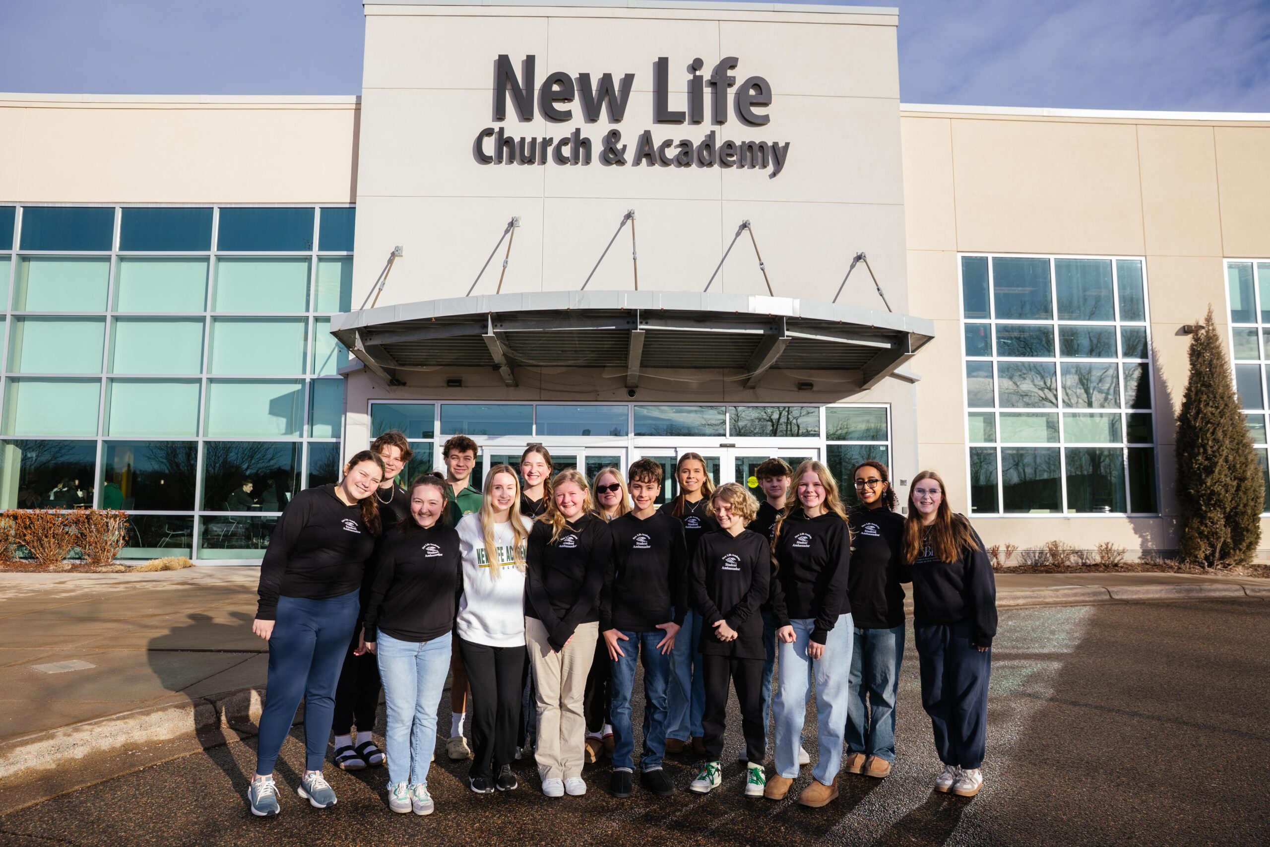 2025–2026 Student Ambassadors standing together in front of New Life Church & Academy building.