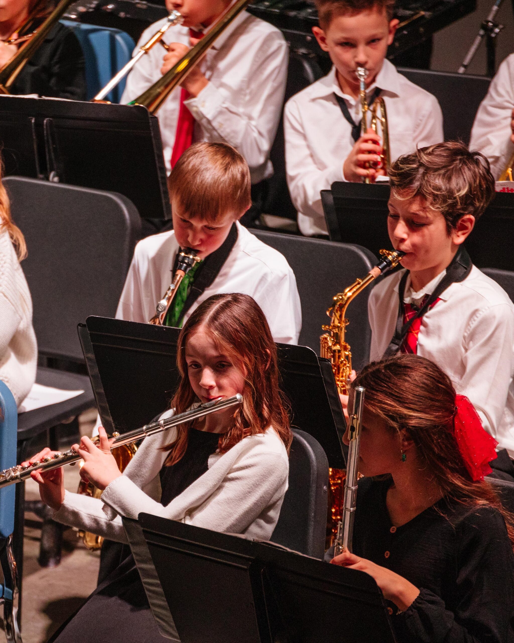 New Life Academy Band students performing on stage during a concert, playing flutes, saxophones, and brass instruments.