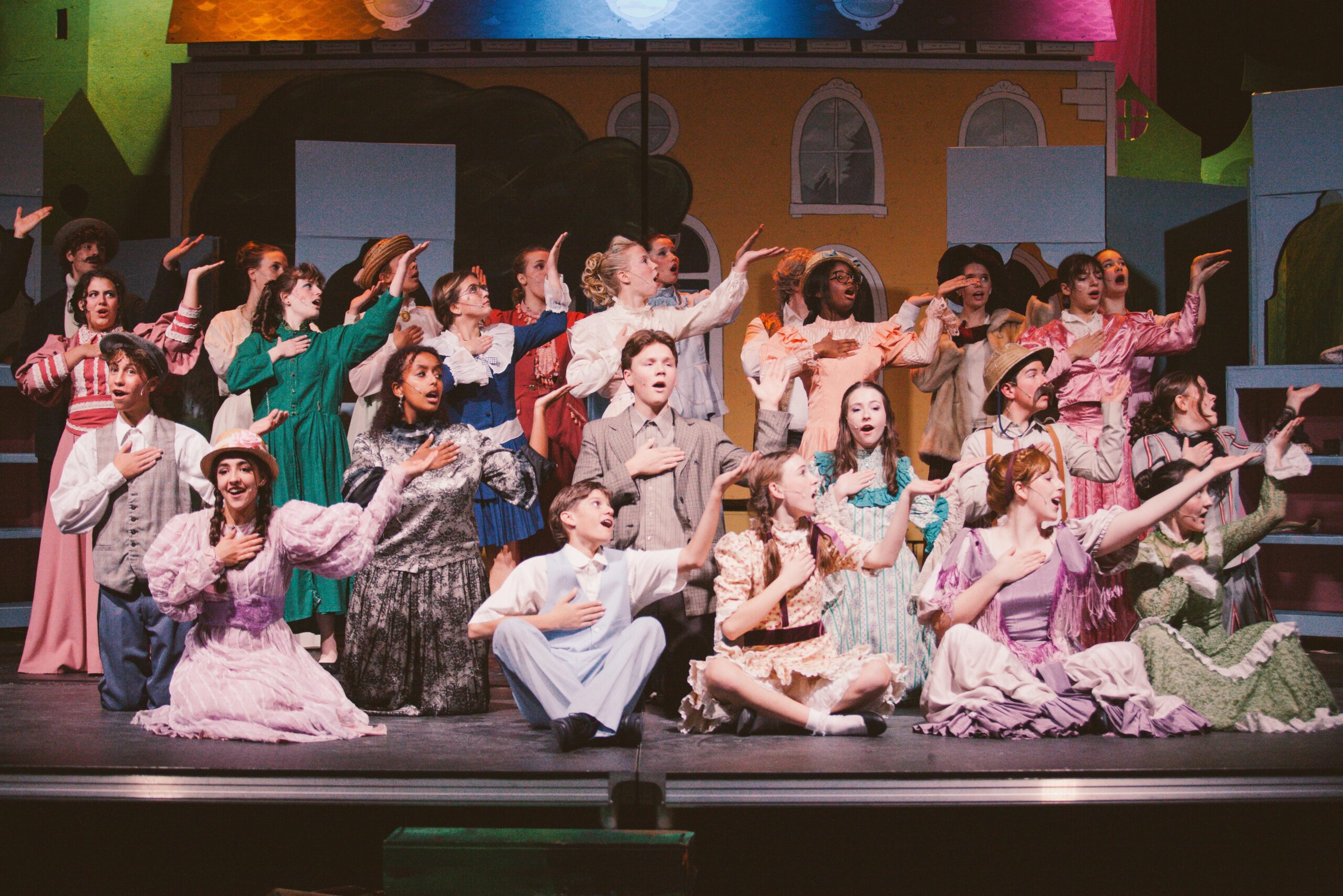 Ensemble cast performs on stage during New Life Academy’s fall 2025 production of Mary Poppins, featuring colorful period costumes and choreographed movement.