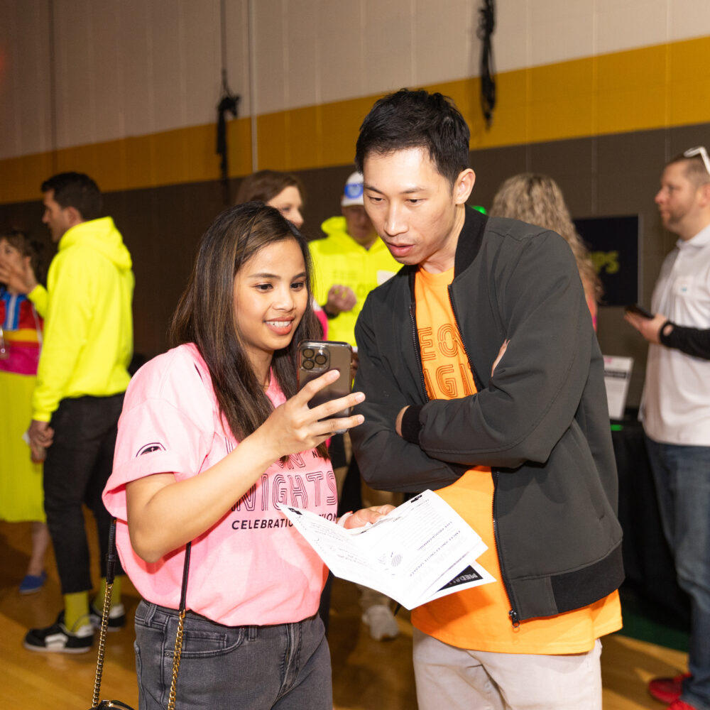 Students at New Life Academy cheerfully walking through a tunnel of raised arms during a school spirit event in the gym.