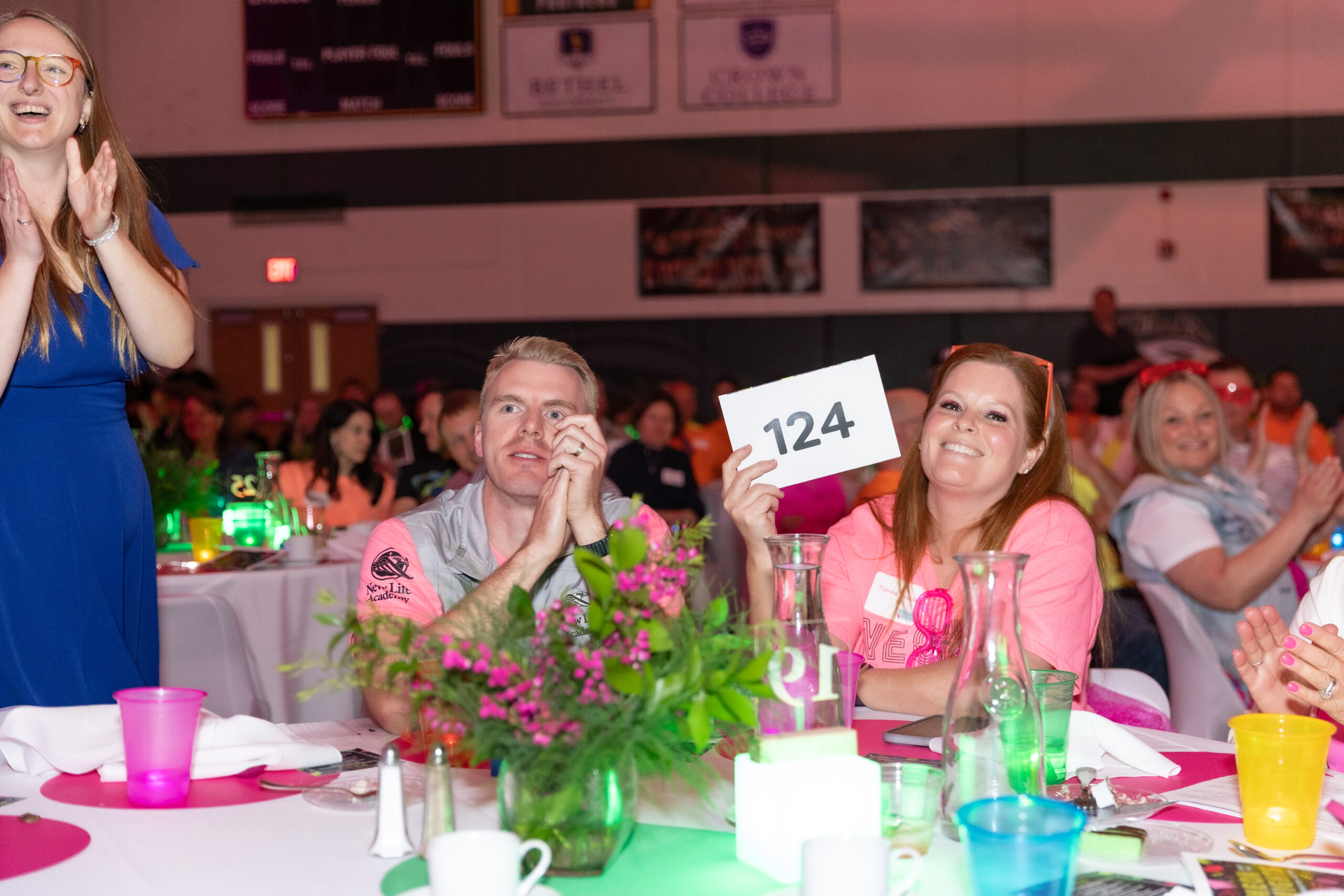 Guests seated in a decorated gym watching the program at New Life Academy’s Neon Nights Celebration Auction.