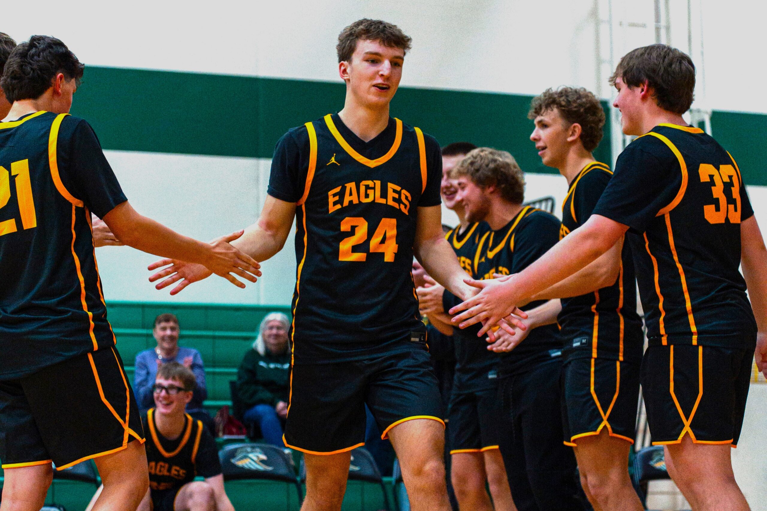 New Life Academy boys varsity basketball players celebrating during a game with teammates on the court