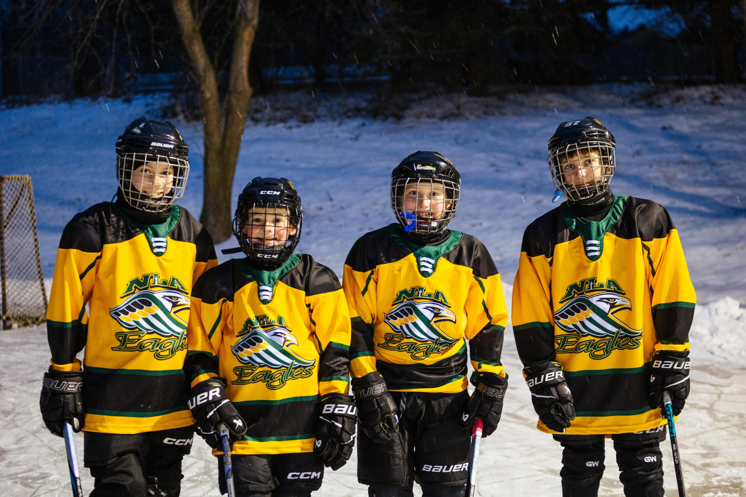 A teacher stands by students discussion a lesson with students seated at desks.