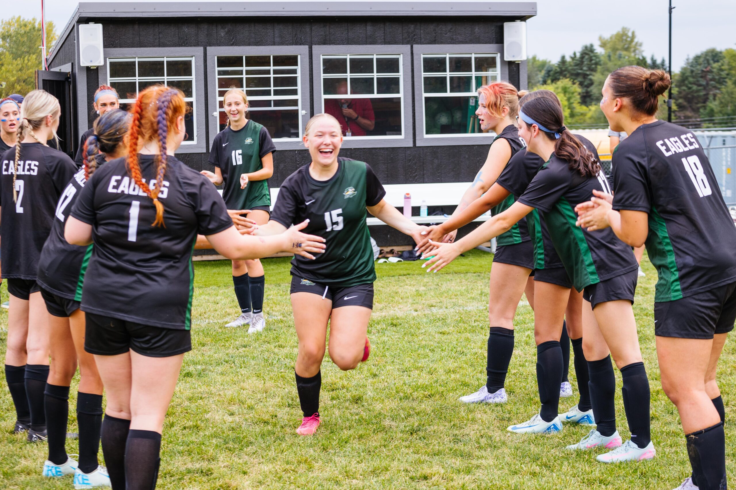 New Life Academy Boys Varsity Baseball Team huddled together on the field during a night game.