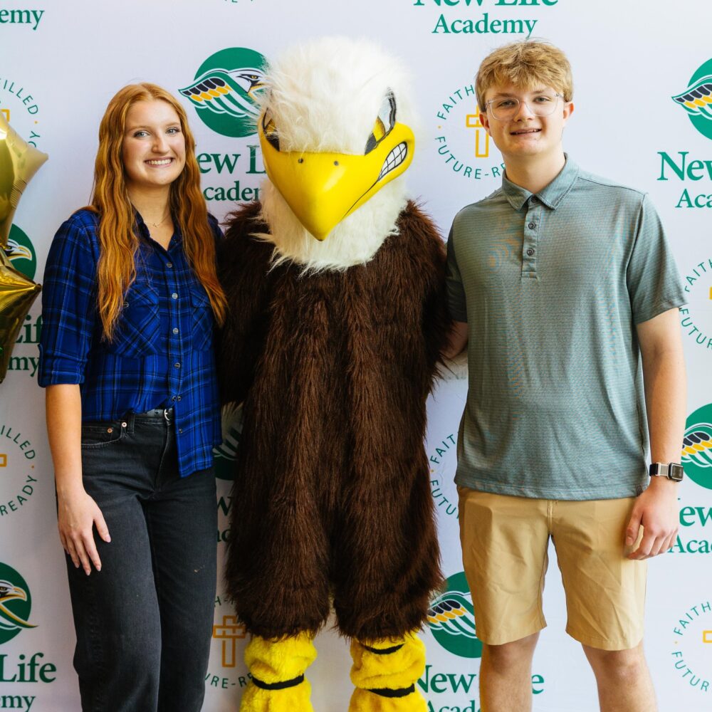 Four New Life Academy students smiling outdoors while holding Annual Fund signs and boxes during the 2025 campaign kickoff.